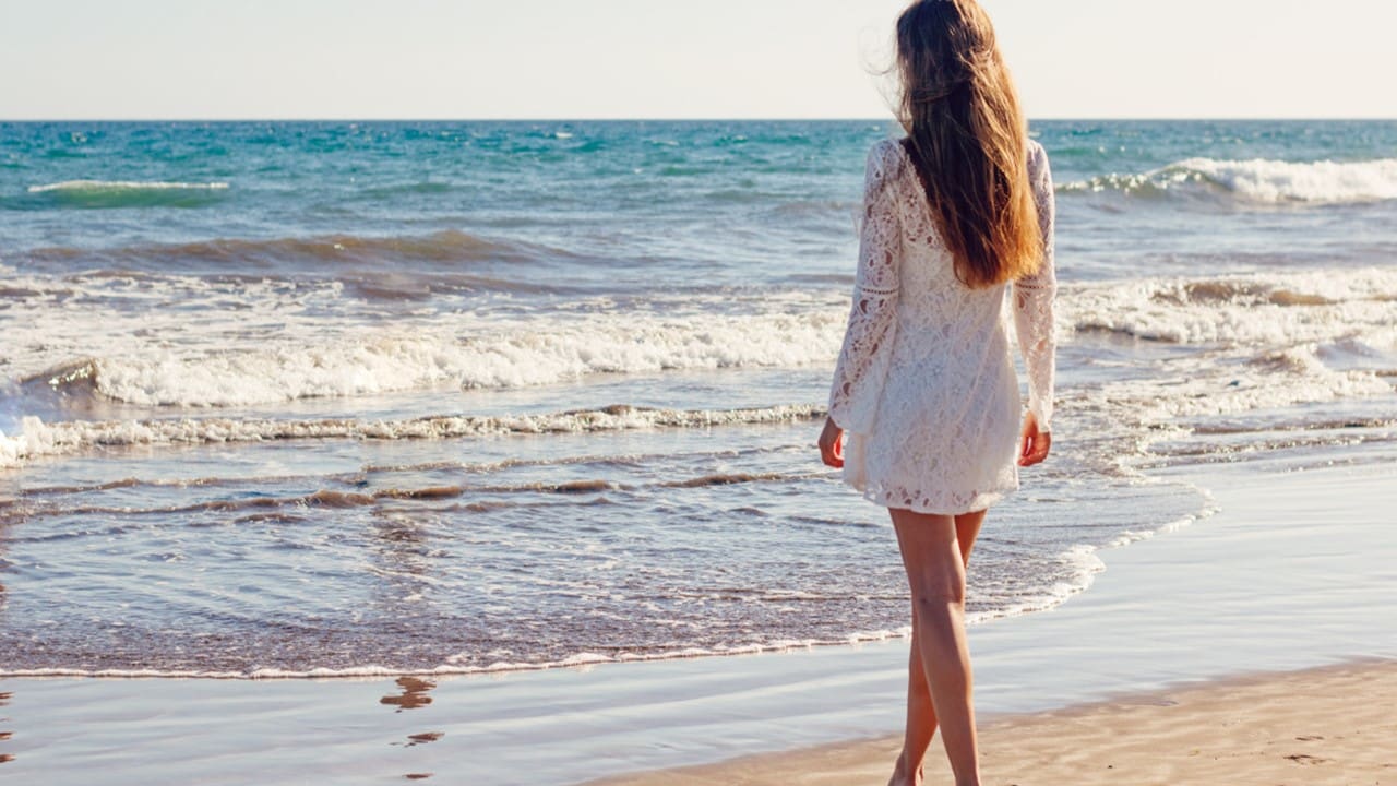 Woman in white lace dress by ocean