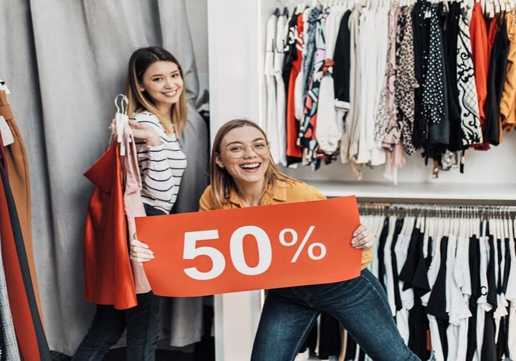 Women in clothing store holding 50% sale sign